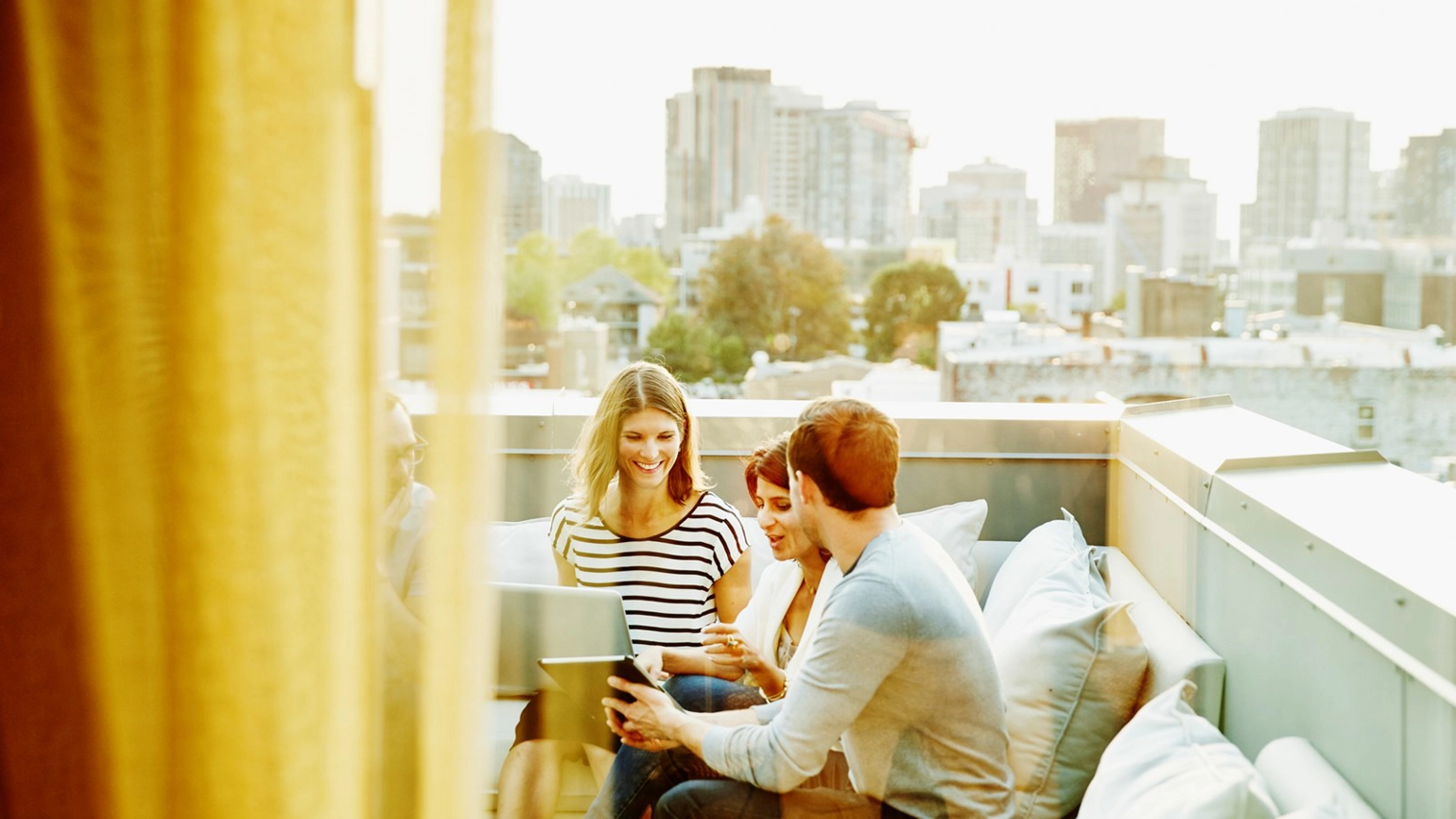Three colleagues working with their laptop in rooftop Three colleagues working with their laptop in rooftop