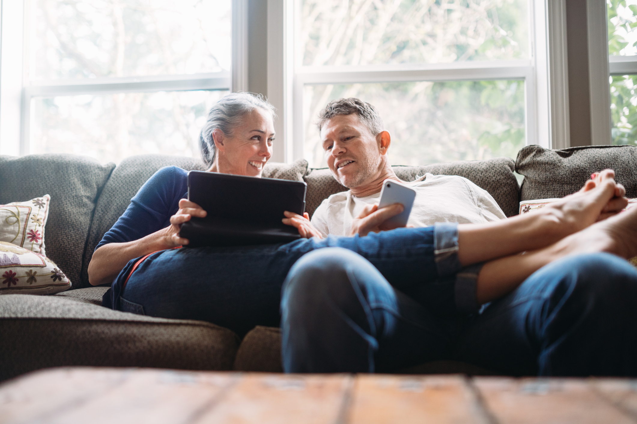 Middle aged couple checking touch screen in living room 