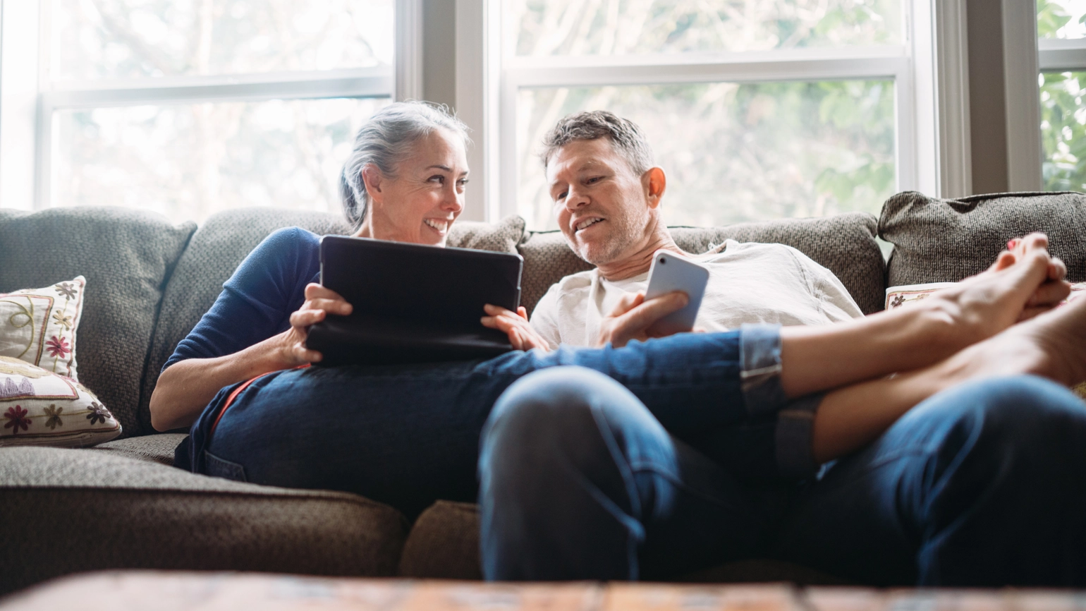 Middle aged couple checking touch screen in living room Middle aged couple checking touch screen in living room
