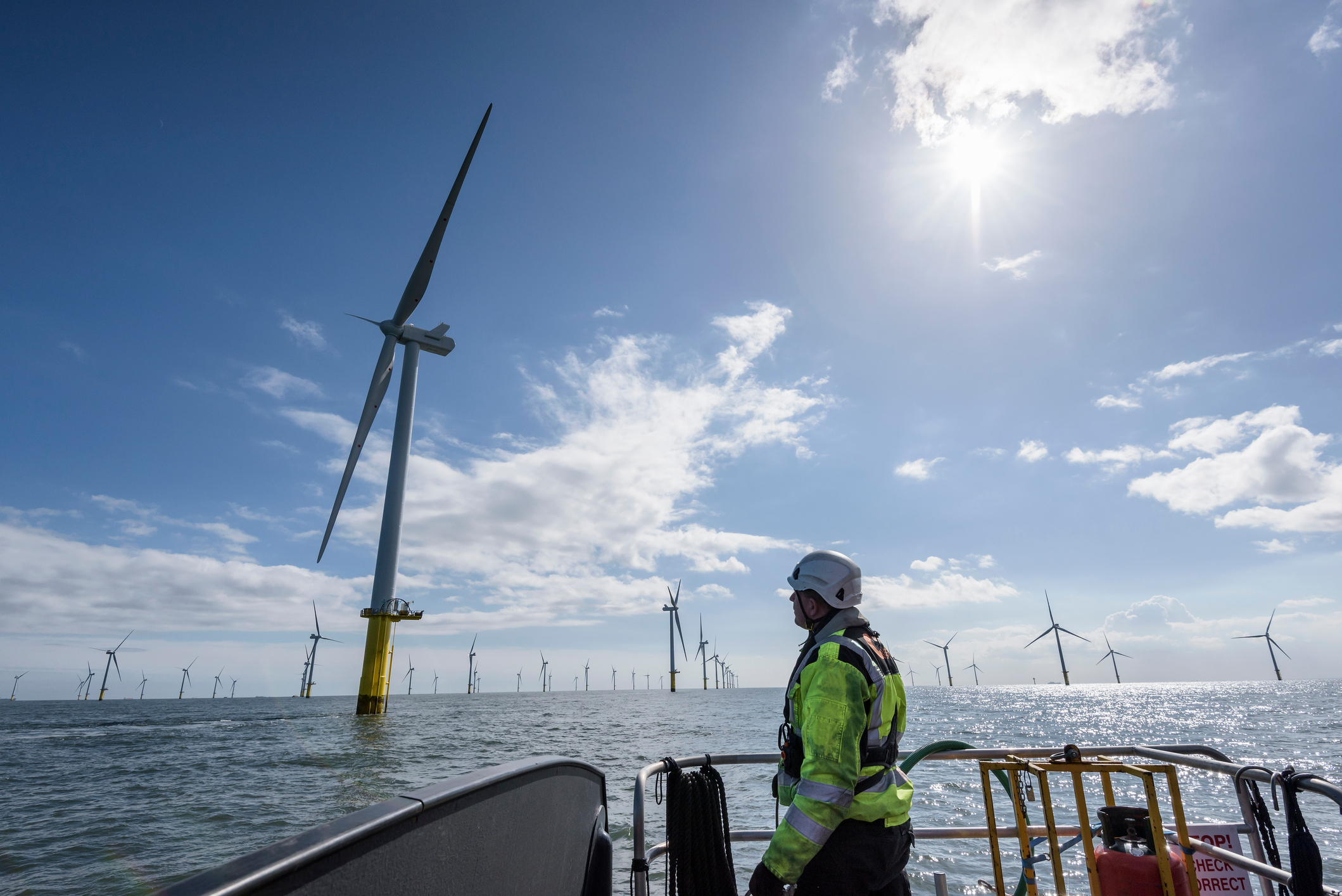 Worker looking out from ship to offshore wind farm