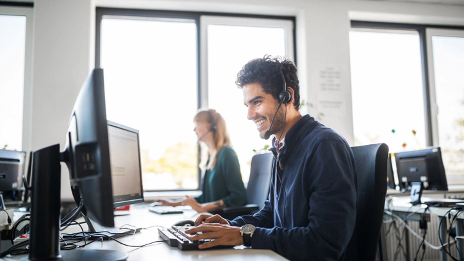 Male worker with headphones working with his desktop Male worker with headphones working with his desktop